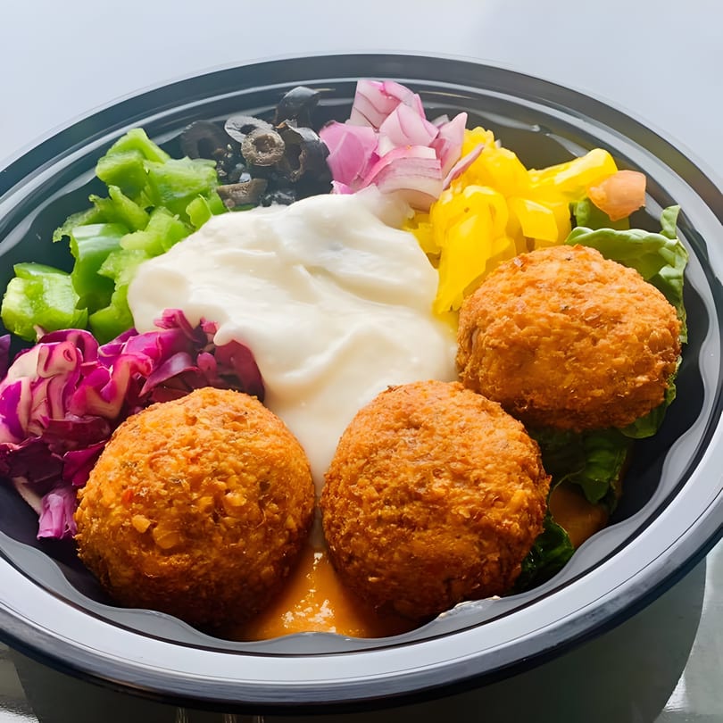 Pita Express falafel bowl with white sauce, red cabbage, green peppers, olives, and red onions.